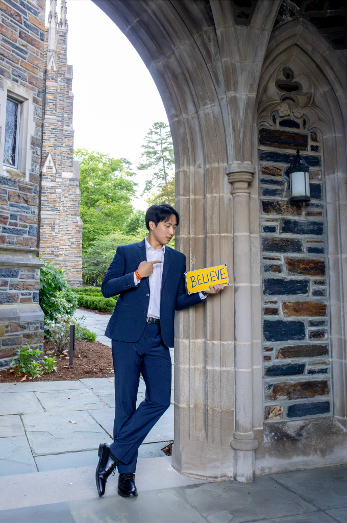 Brent Yoo holding a BELIEVE sign