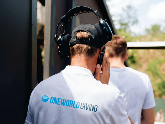 OneWorld Giving event staff member wearing branded polo shirt and headphones