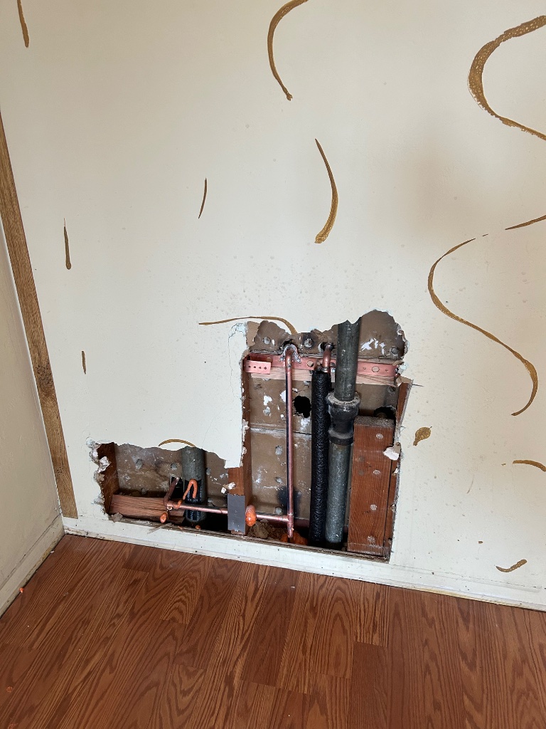 Wall cavity opened showing new copper pipes and old galvanized line