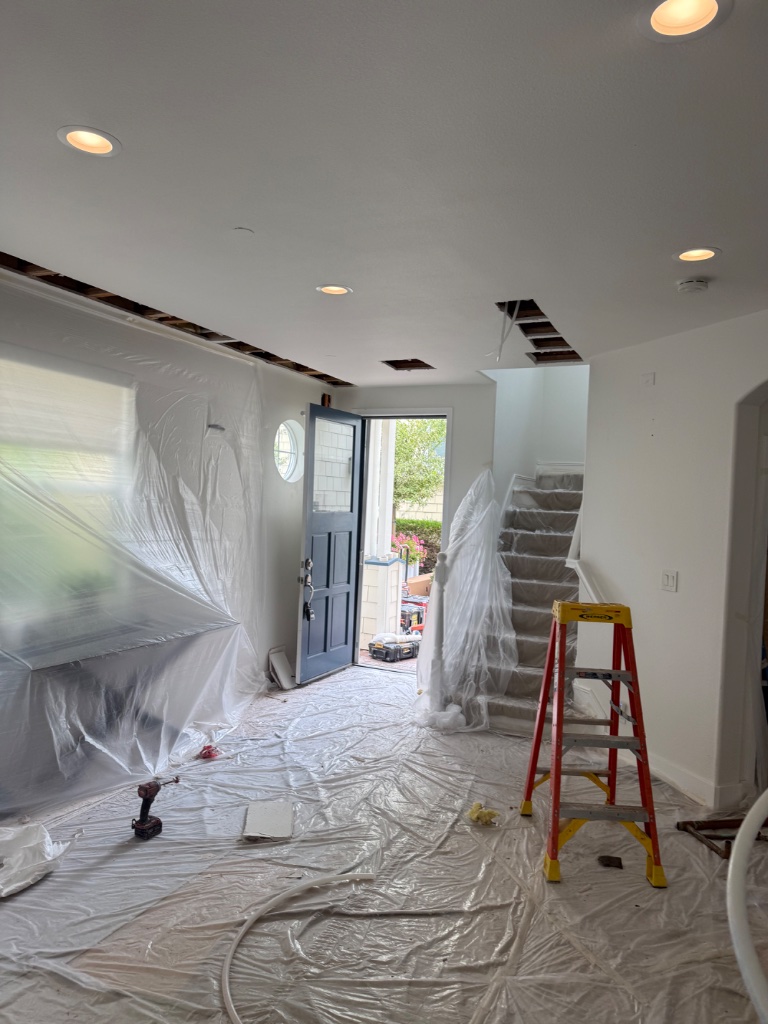 Open foyer with ceiling access holes and crew working inside