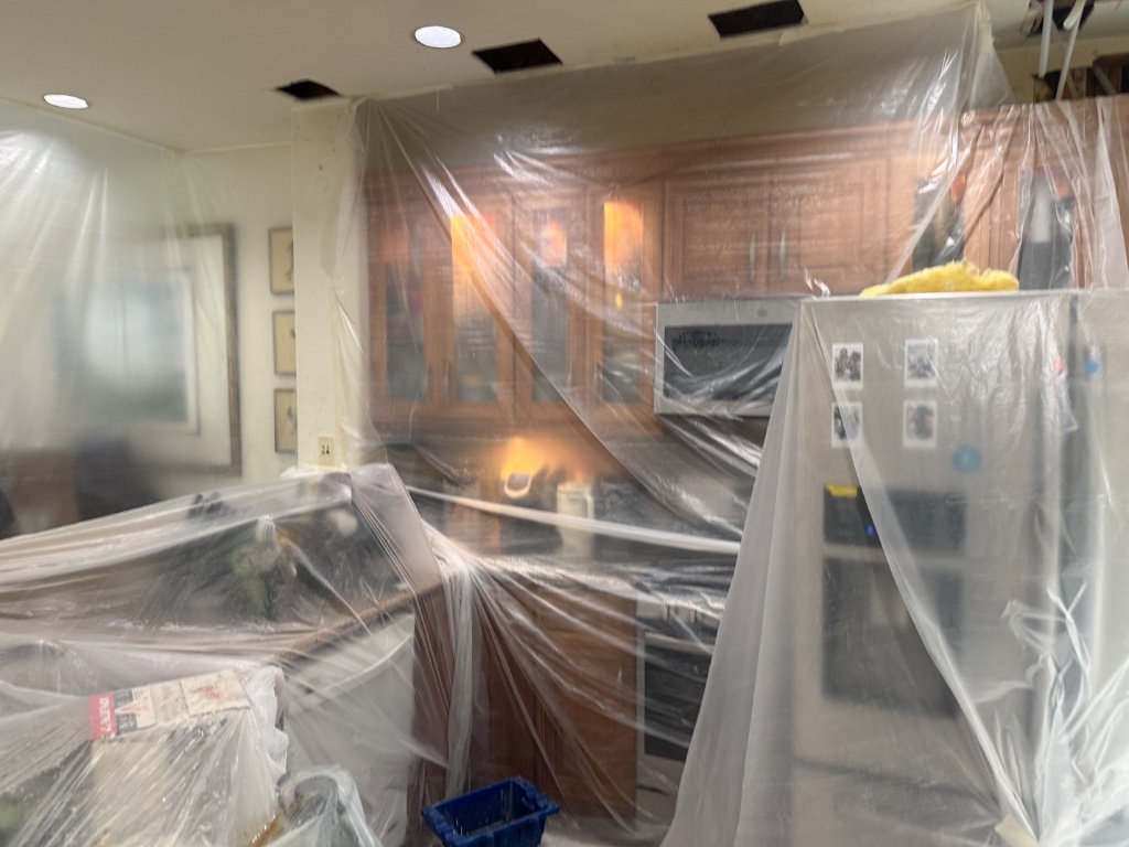 Full kitchen wrapped in plastic sheeting during whole-home repipe