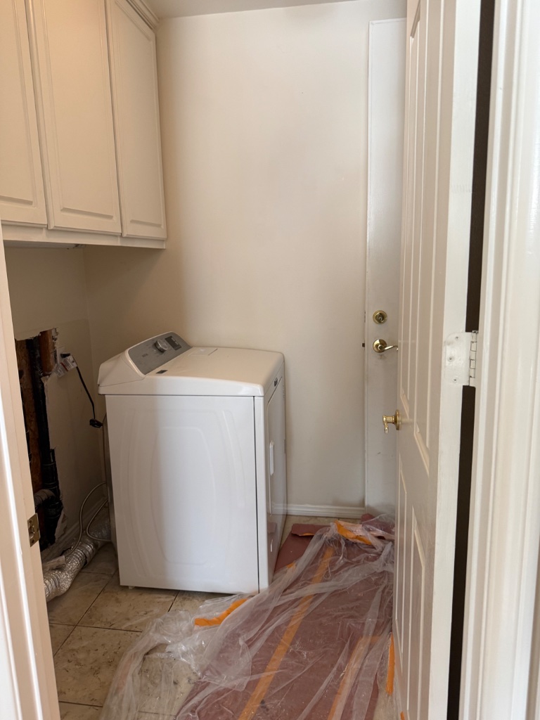 Laundry room with wall opening for new supply line installation