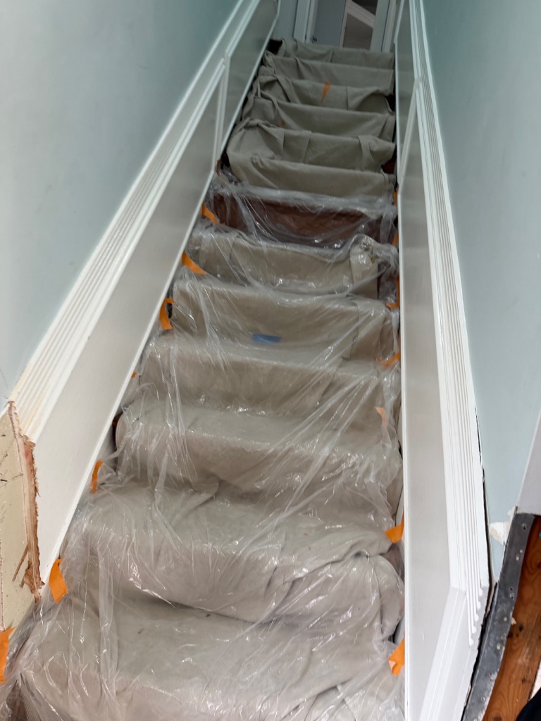 Staircase protected with plastic sheeting during repipe work