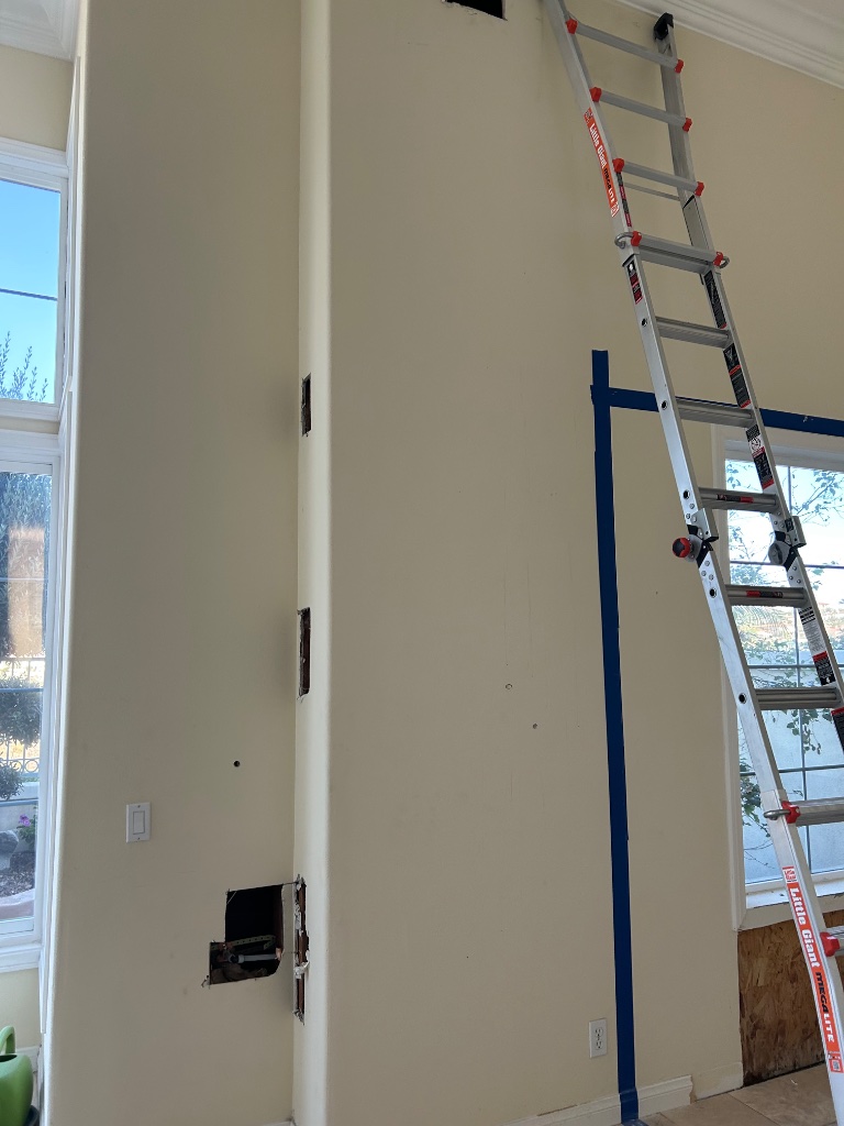 Home interior with ladder and wall opening for pipe installation