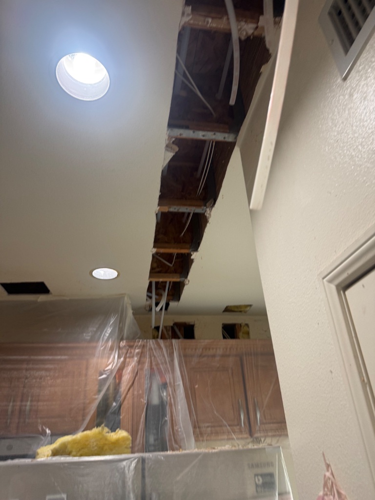 Kitchen ceiling opened with plastic protection over cabinets and appliances