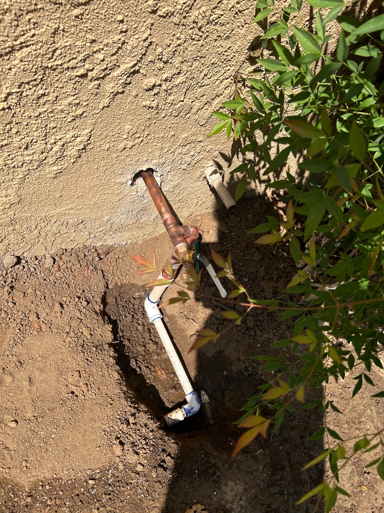 Mainline trench through front yard — new blue PEX water line laid in with caution tape