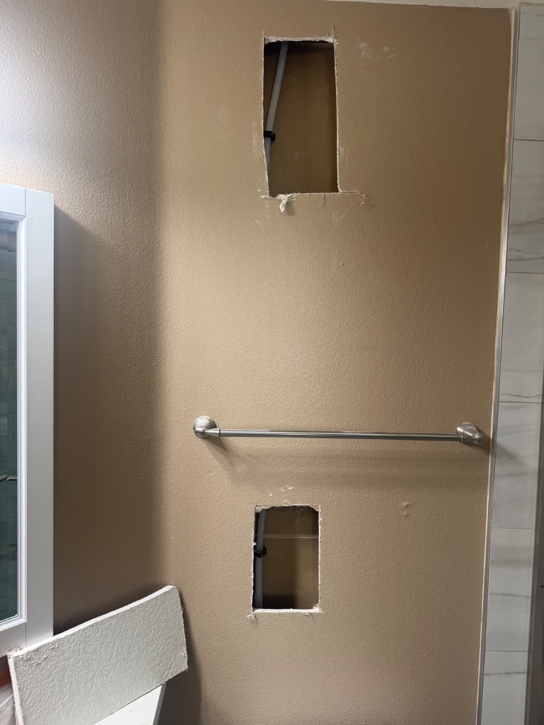 Bathroom vanity, mirror, and fixtures wrapped in plastic for protection
