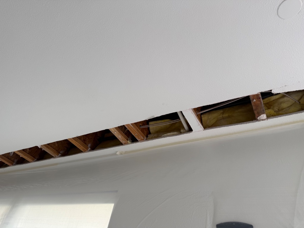 Ceiling strip access with new PEX pipe runs and insulation visible