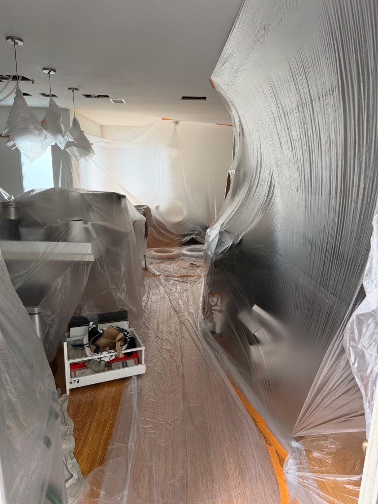 Living room kitchen area protected with plastic barriers during repipe