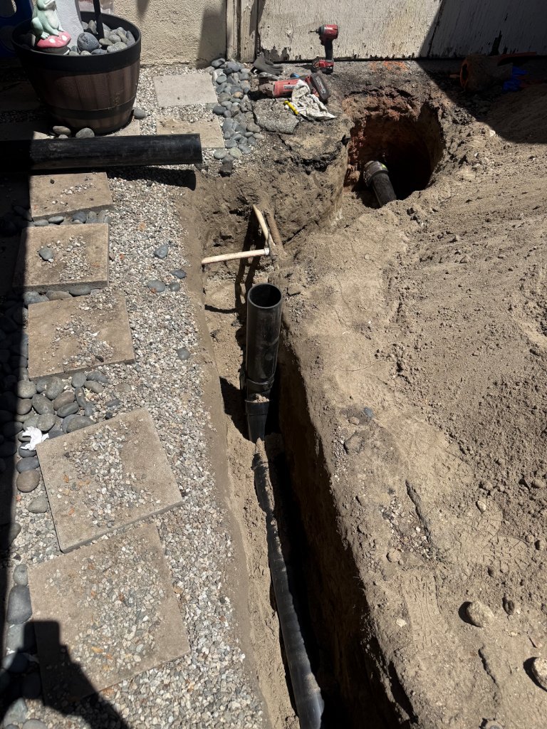 Sewer line replacement trench dug through yard with new ABS pipe