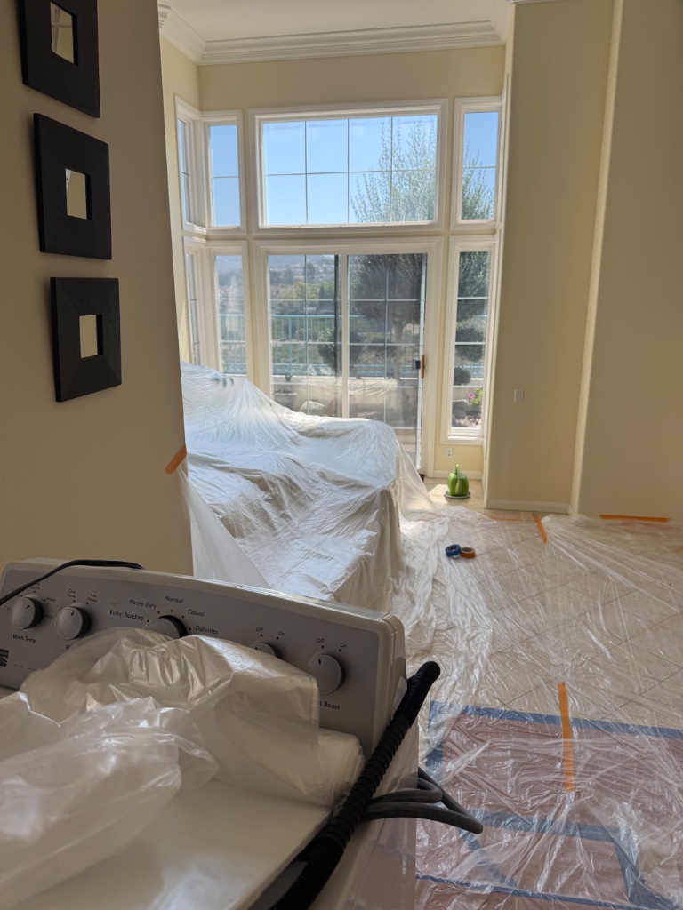 Bright living room fully protected with drop cloths and plastic during repipe