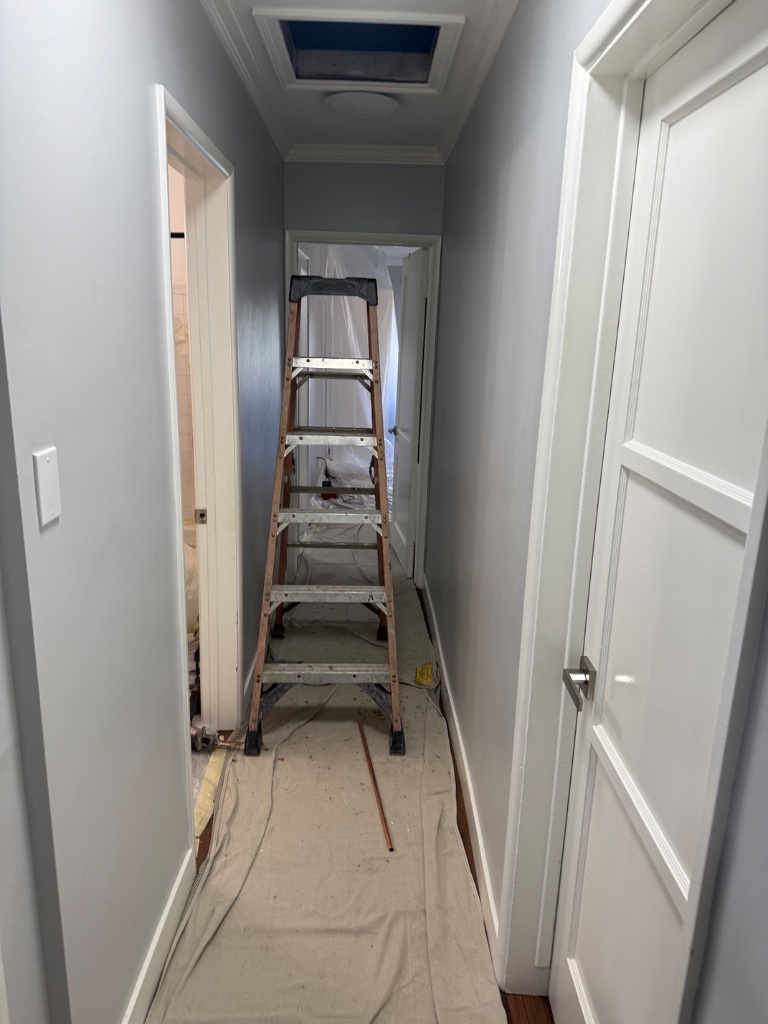 Kitchen fully wrapped in plastic — tile floors covered with drop cloths