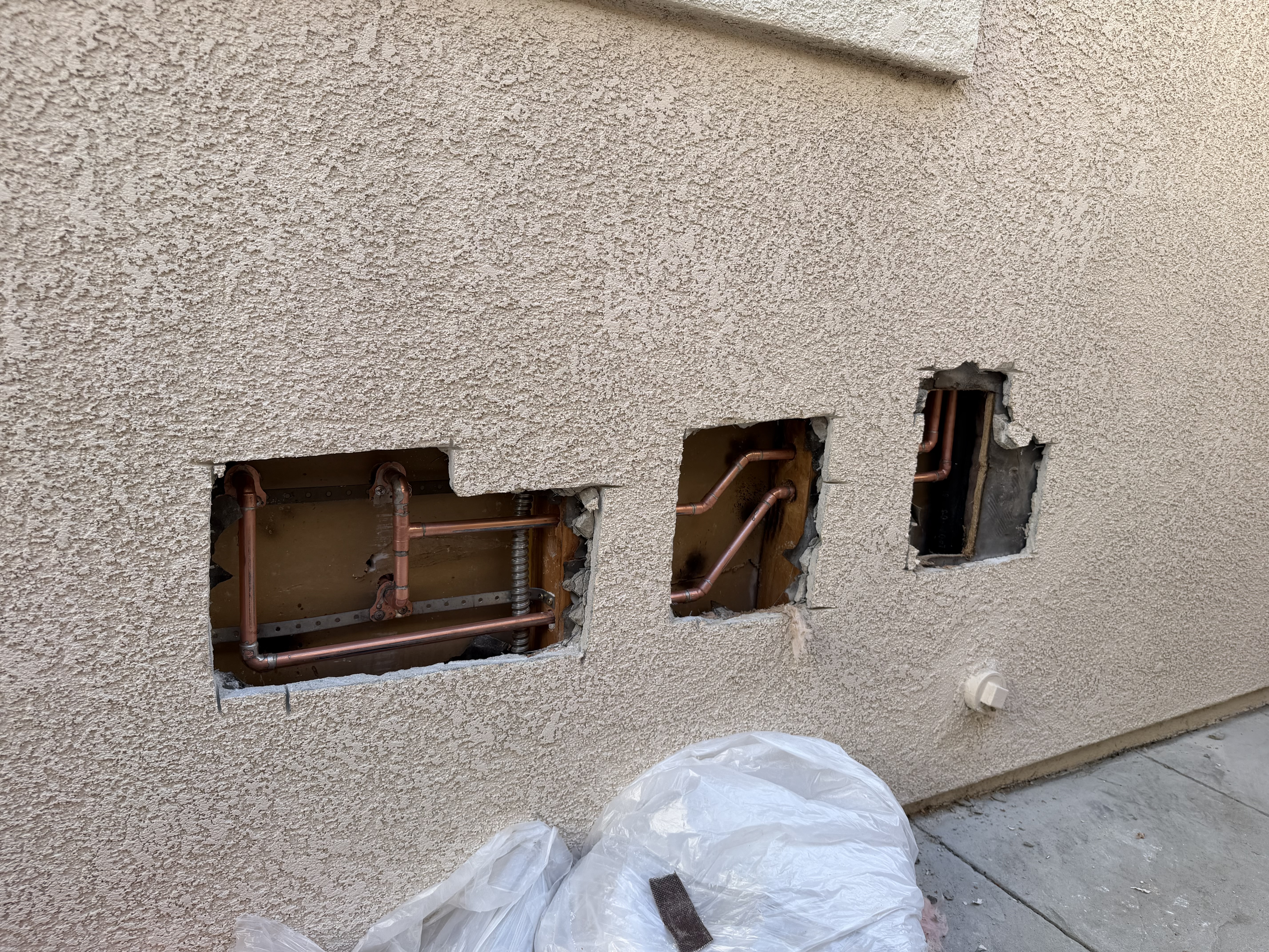 Copper repipe installation showing new copper pipes in exterior stucco wall cutouts