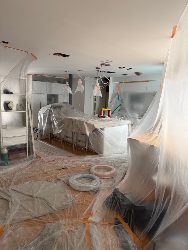 Kitchen fully sealed with drop cloths and protective plastic sheeting
