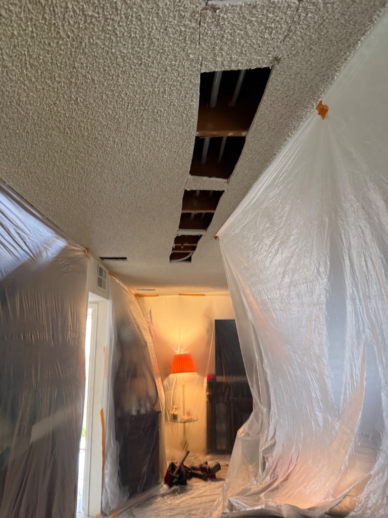 Hallway ceiling opened with multiple access holes for overhead pipe routing