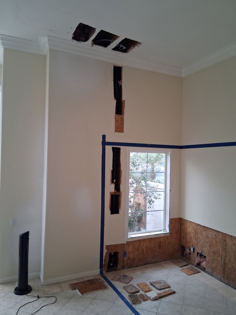Large wall section opened showing PEX and copper pipe routing during repipe