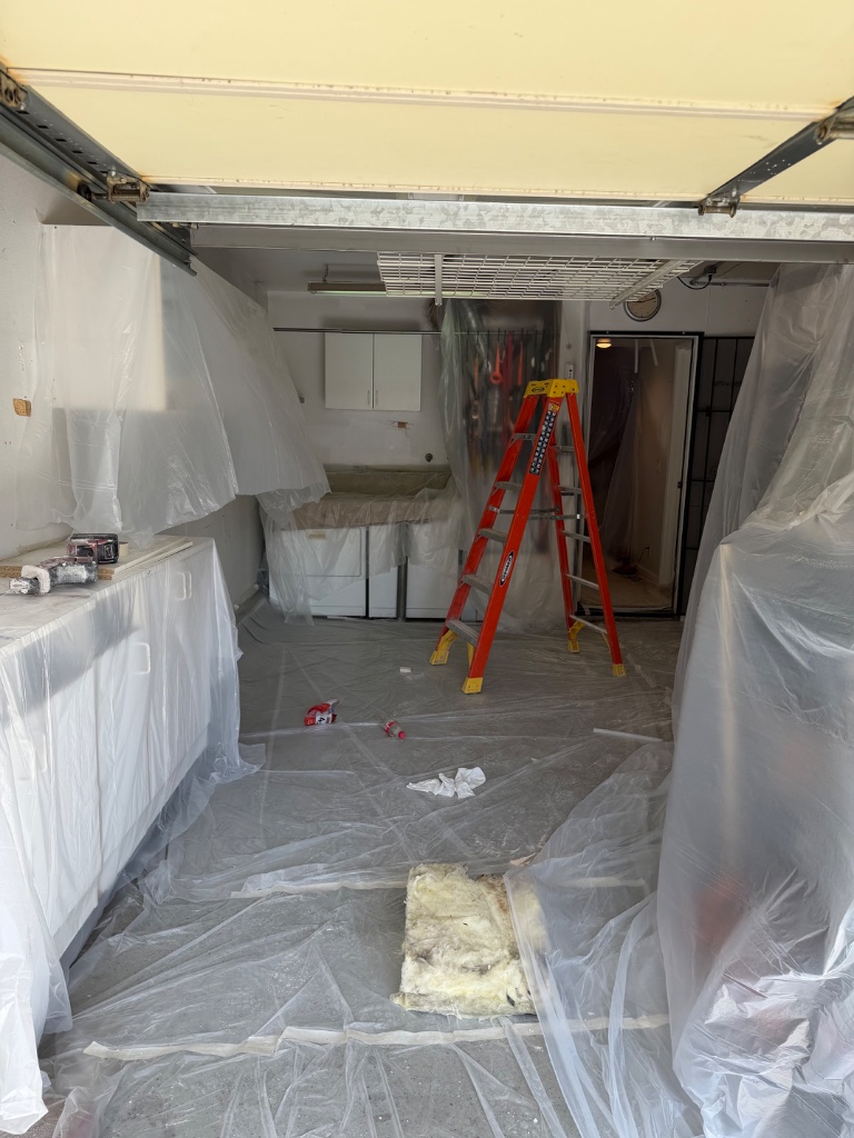 Garage utility room protected — ladder staged, appliances and cabinets wrapped