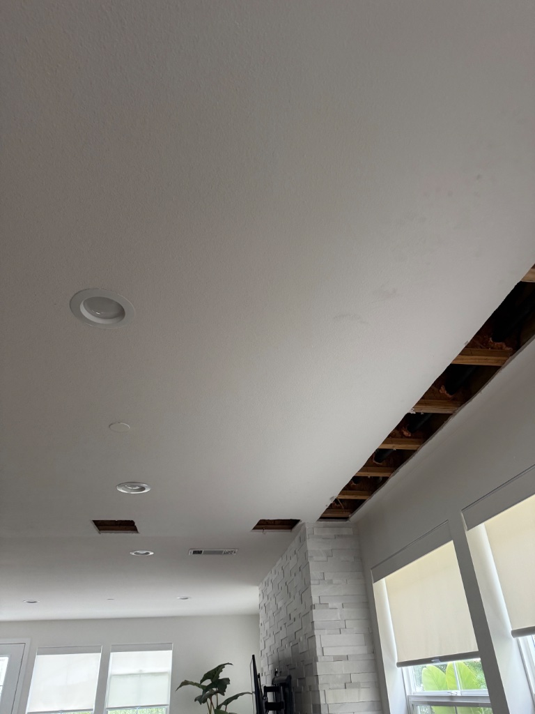 Ceiling access strip cut for overhead PEX routing — patched and painted clean