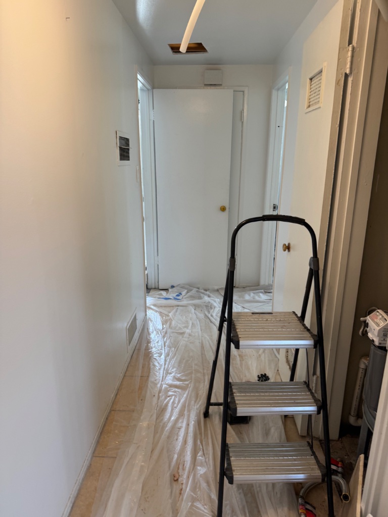 Utility hallway with ceiling access and floor protection during repipe
