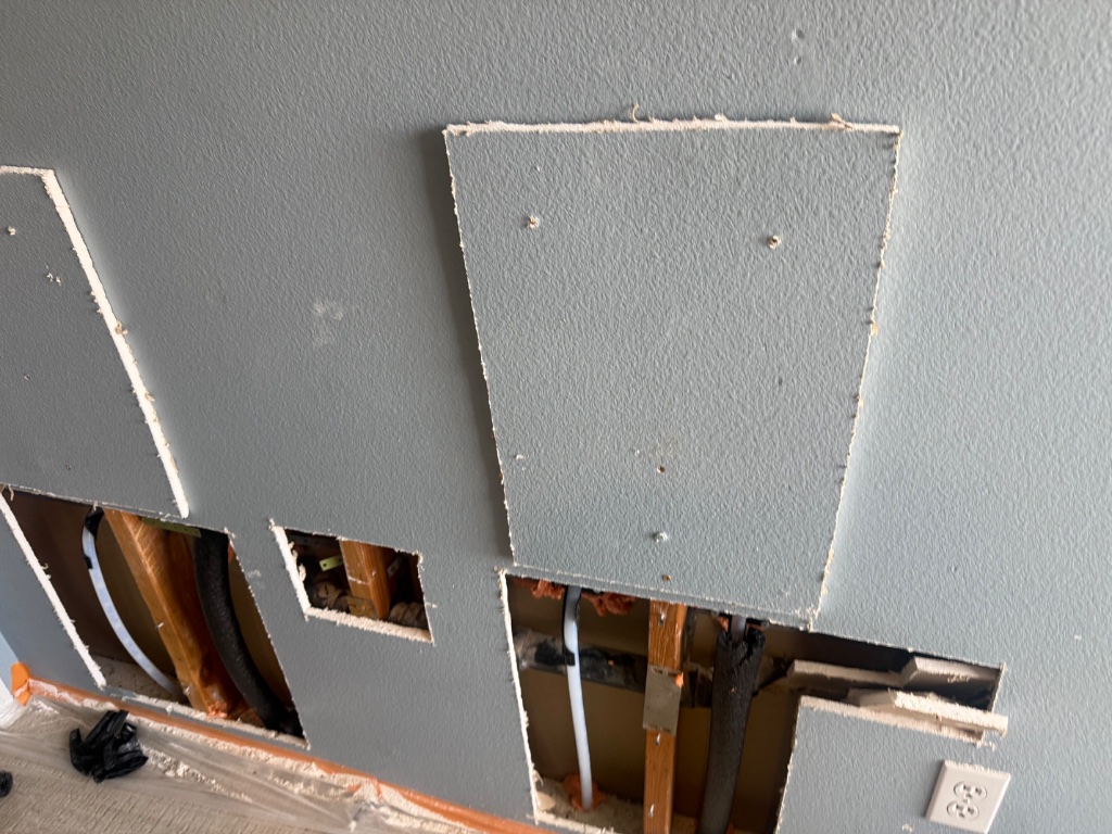 Multiple wall access holes with drywall patches ready for texture and paint