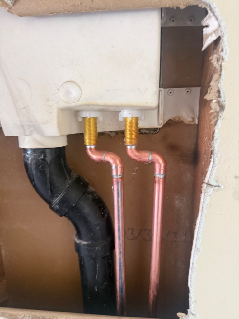 Multiple rectangular wall access holes cut in hallway for pipe routing