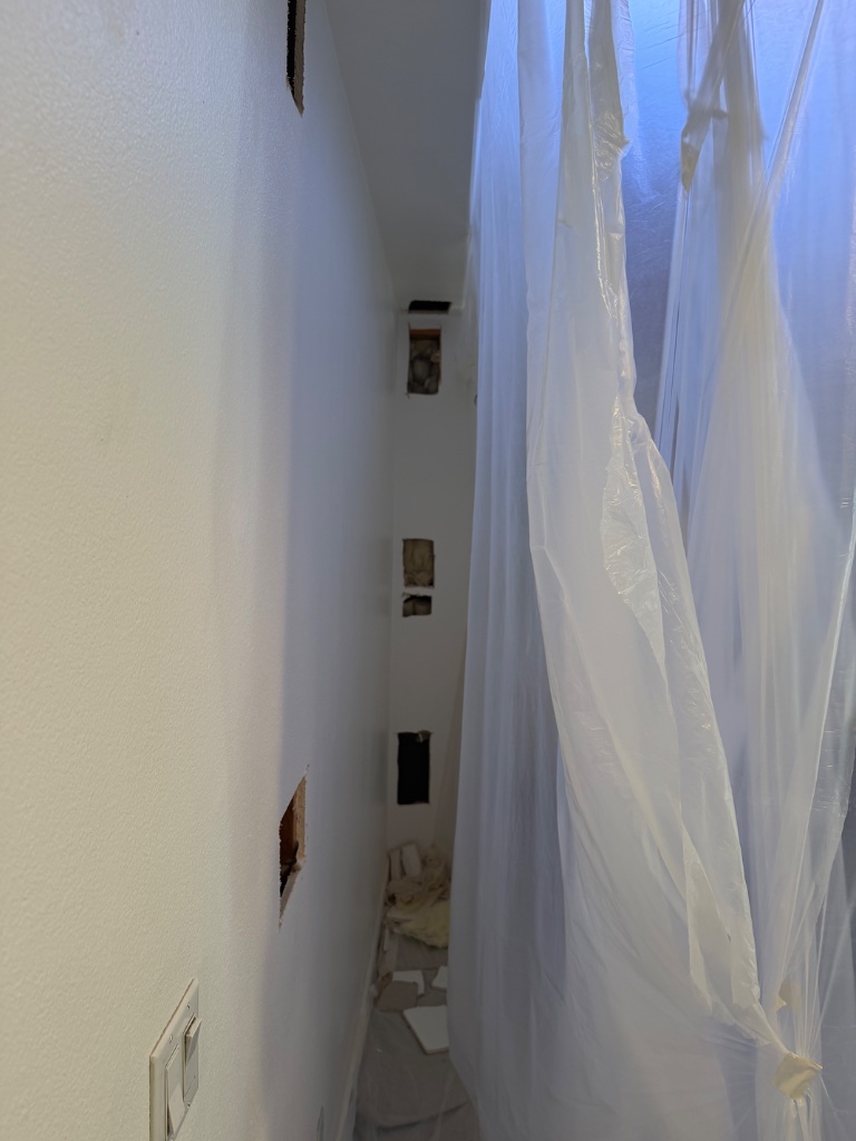 Vertical wall access cuts with plastic dust barrier in place during repipe