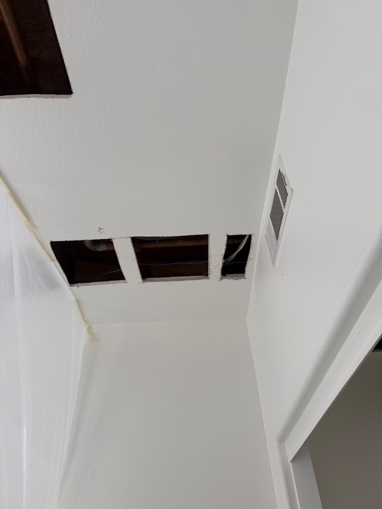 Hallway ceiling access holes showing clean pipe routing