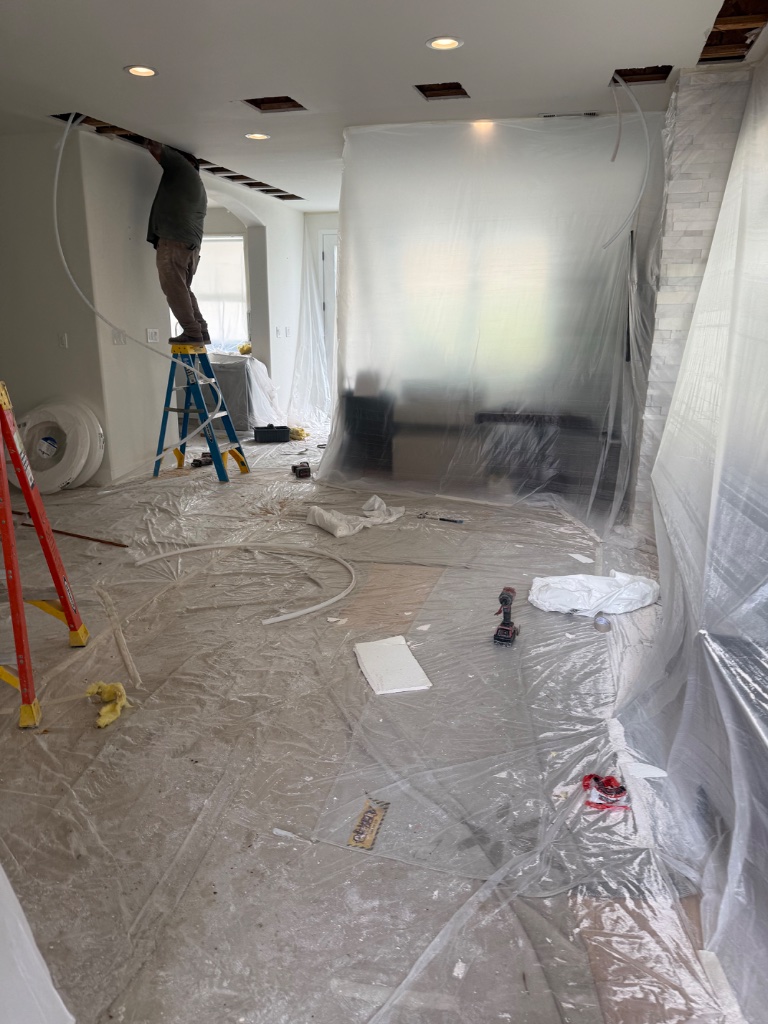 Technician running new PEX supply lines through ceiling access opening