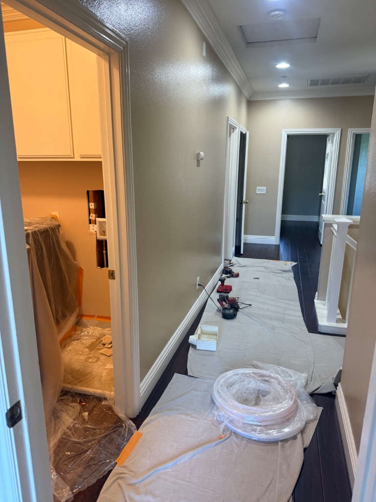 Upstairs hallway with PEX coil and tools staged for repipe installation