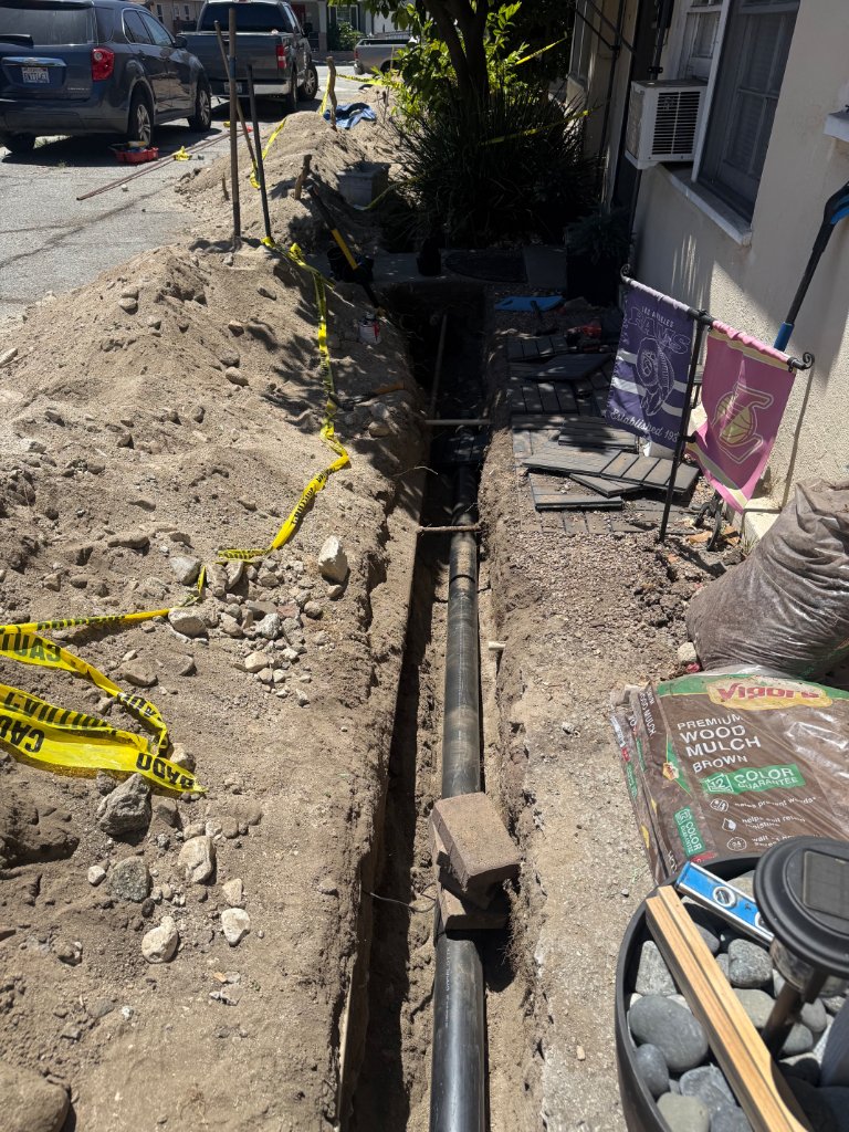 Full sewer line trench running from house to street with caution tape
