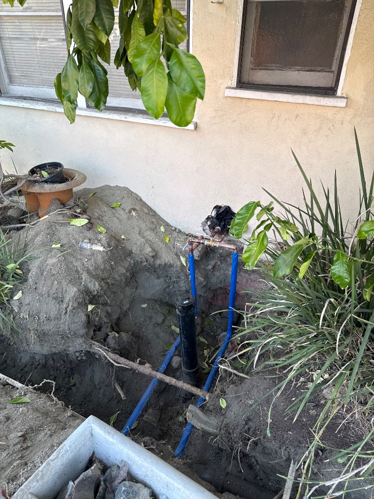 Exterior mainline trench with new blue PEX water line and copper connections