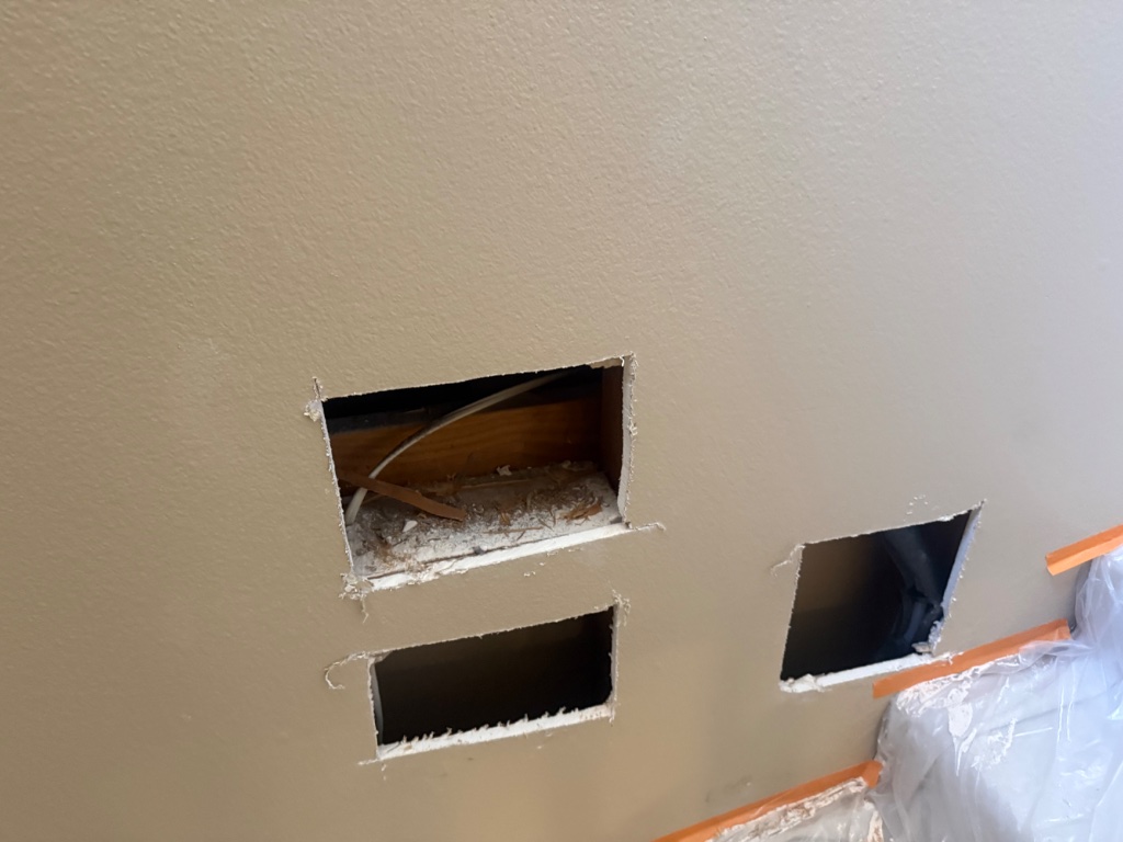Under-sink cabinet open showing new supply line connections after repipe