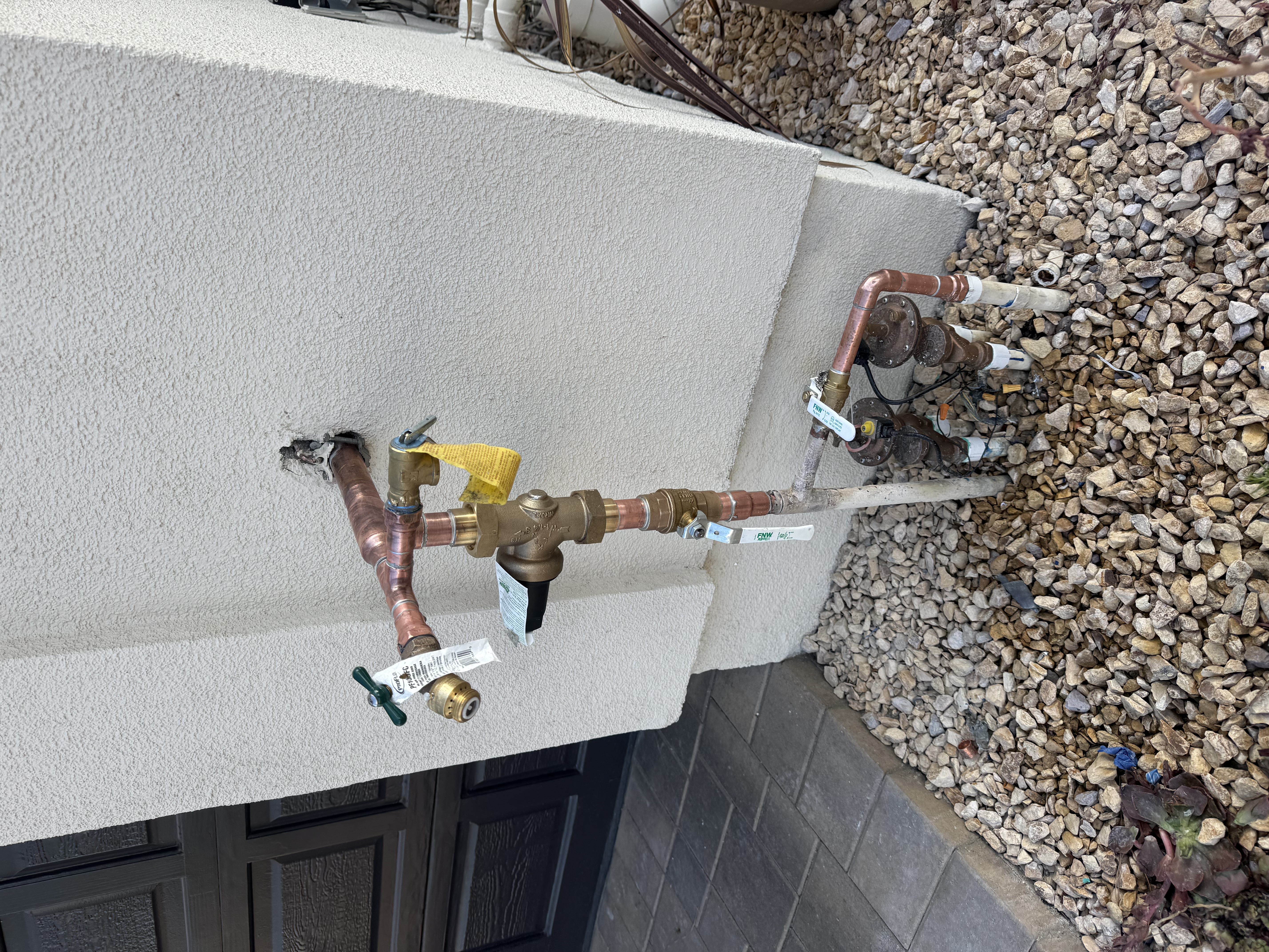Type L copper pipe installation with ball valves and pressure regulator on stucco wall