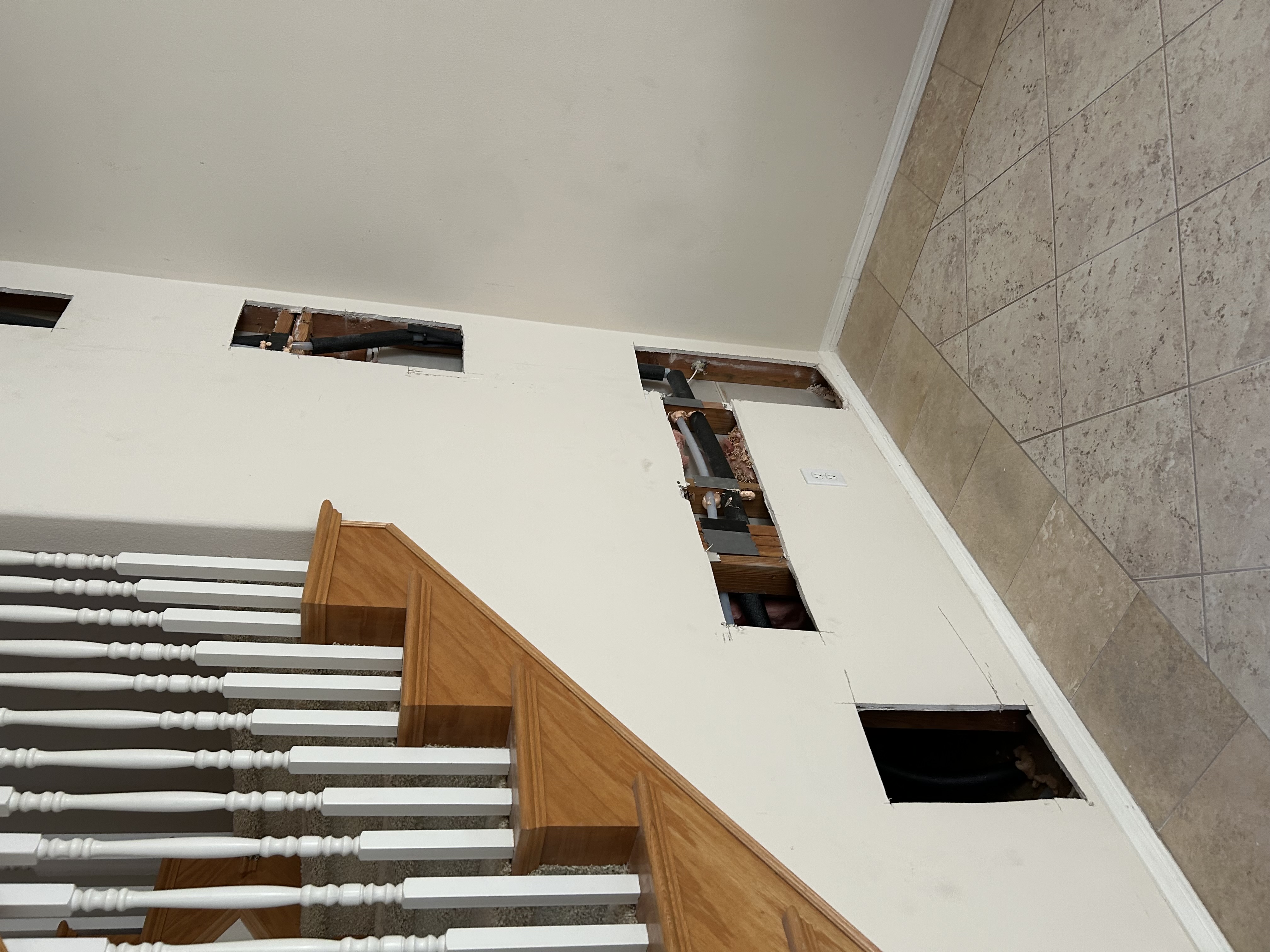 Ceiling and wall openings exposing joists during a PEX-A repipe