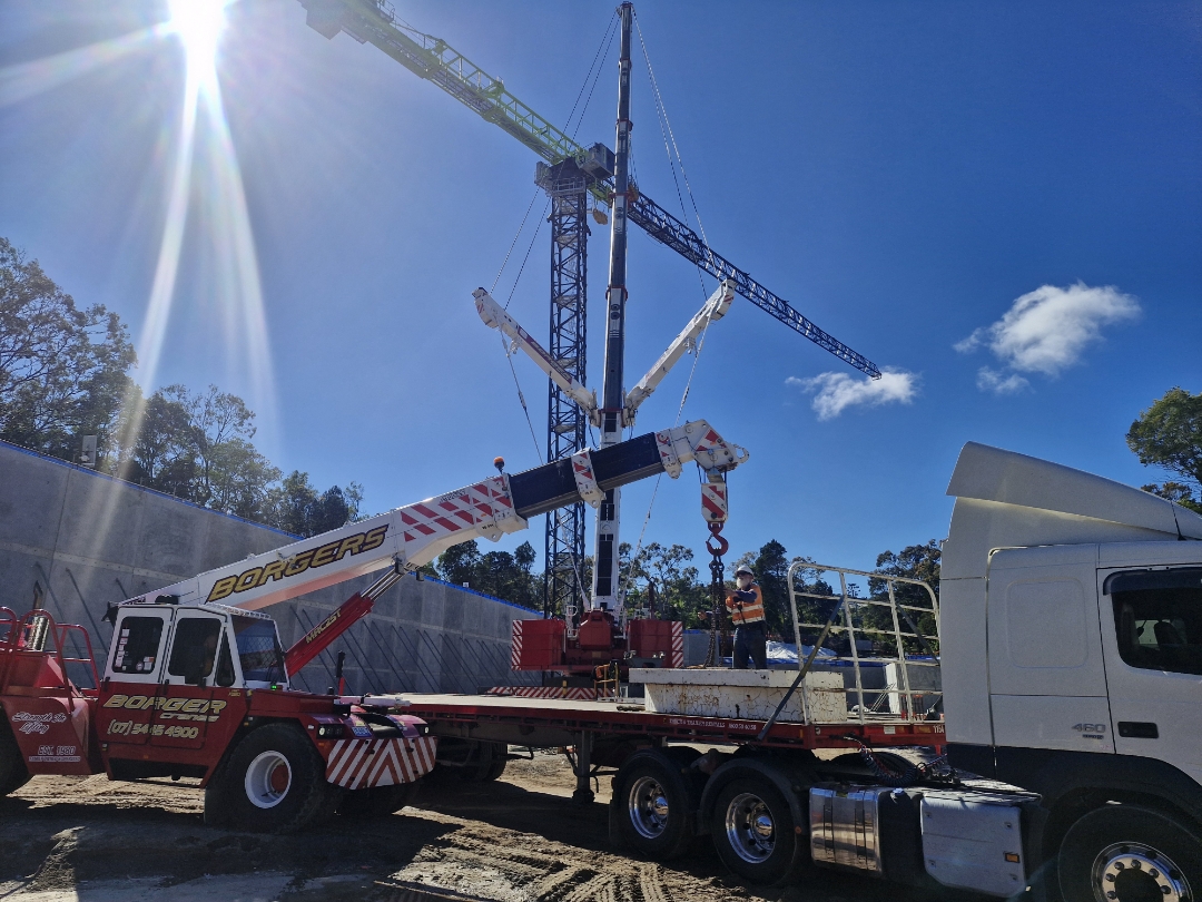 Borgers mobile crane lifting a modular component onto a flatbed trailer at a Brisbane construction site