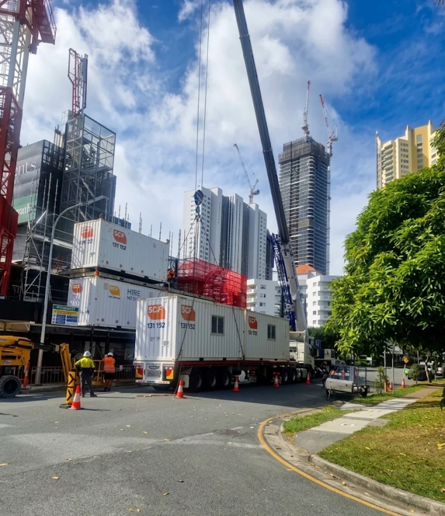 SCF shipping containers lifted by mobile crane onto a flatbed trailer on a Brisbane street