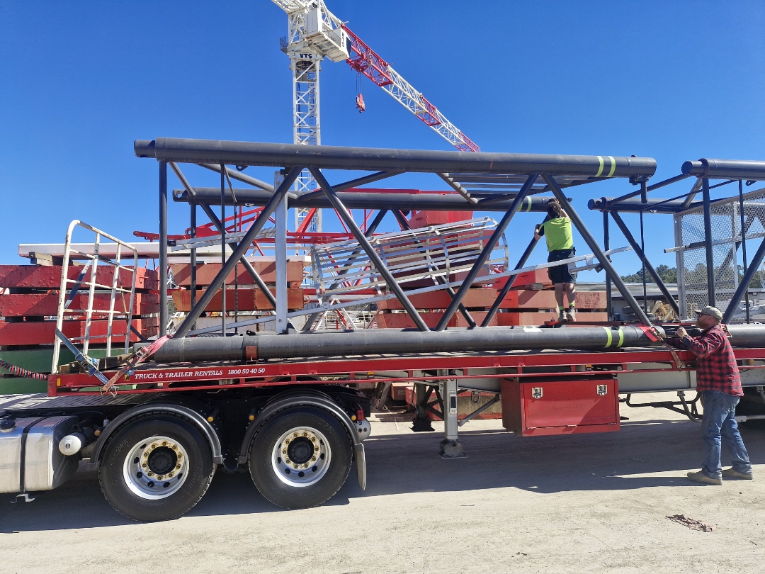 AFM crew securing a tower crane lattice truss onto a flatbed trailer on site