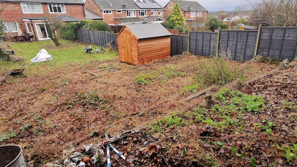 Neglected rear garden before tidy up - debris, dead leaves and overgrowth in Basingstoke