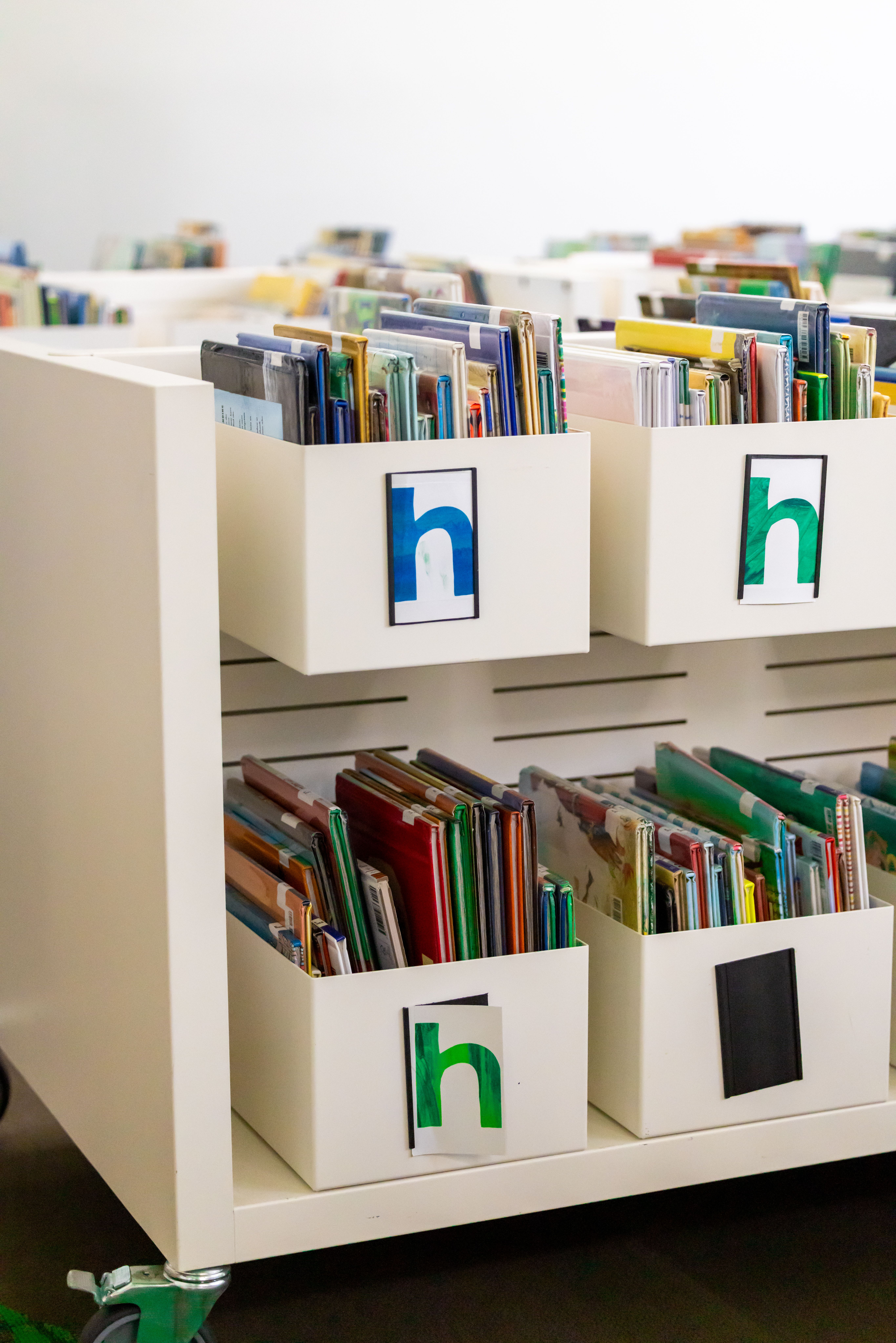 Rolling white book cart filled with children's books