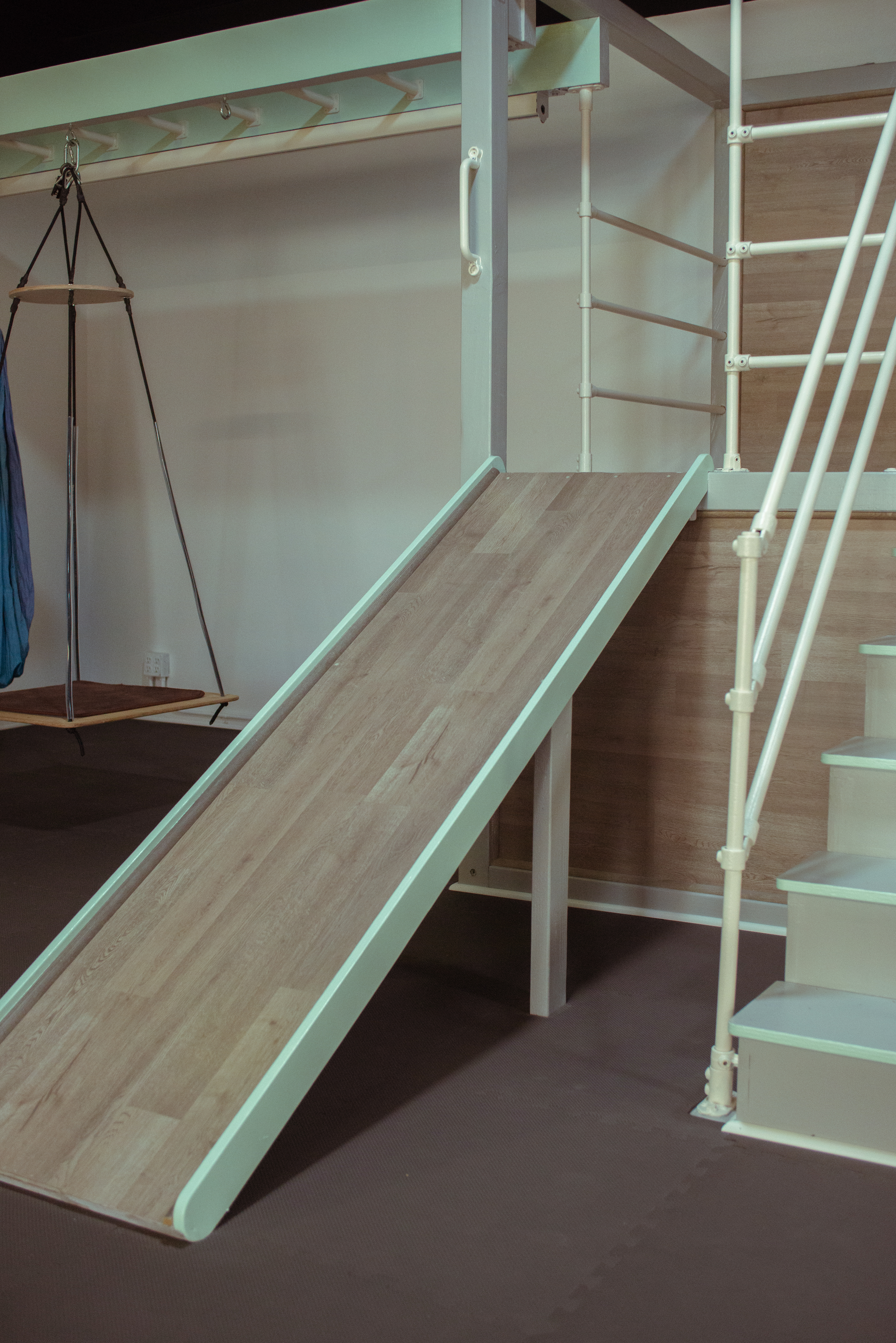 Wooden play structure with slide, swing, and stairs