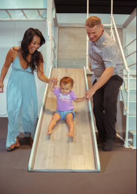 A family sliding together in the custom sensory gym at Illuminate Studios