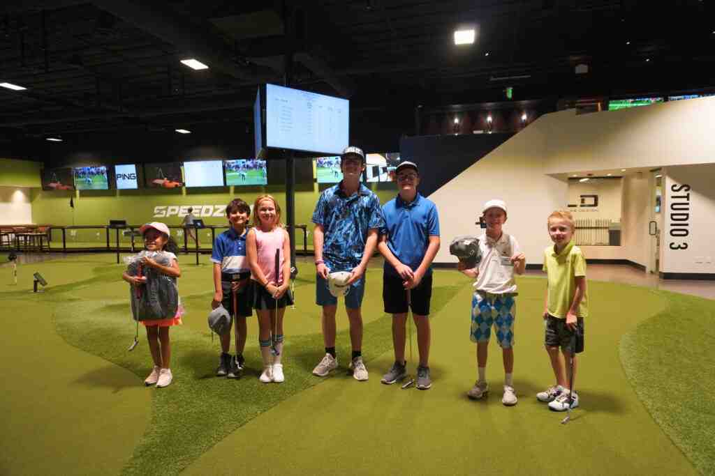 A group of young golfers with their putters on an indoor Putting World green.