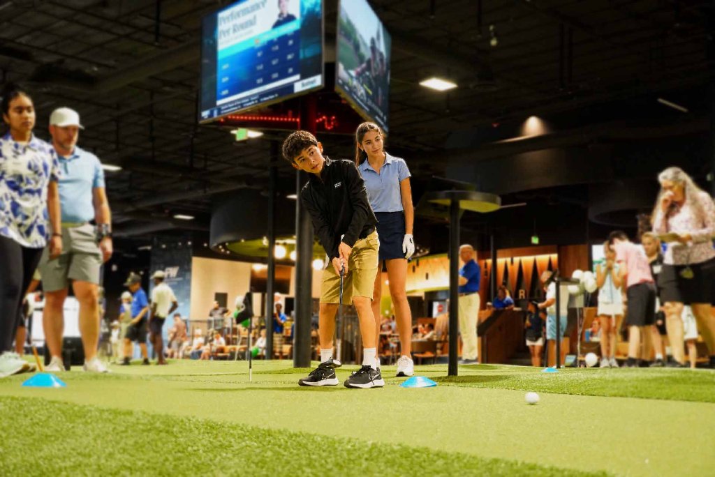 A young golfer putting on the indoor putting course at Putting World