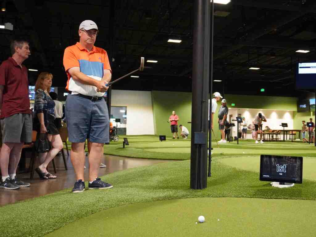 A golfer holding a putter in a steady putting stance on an indoor putting green.