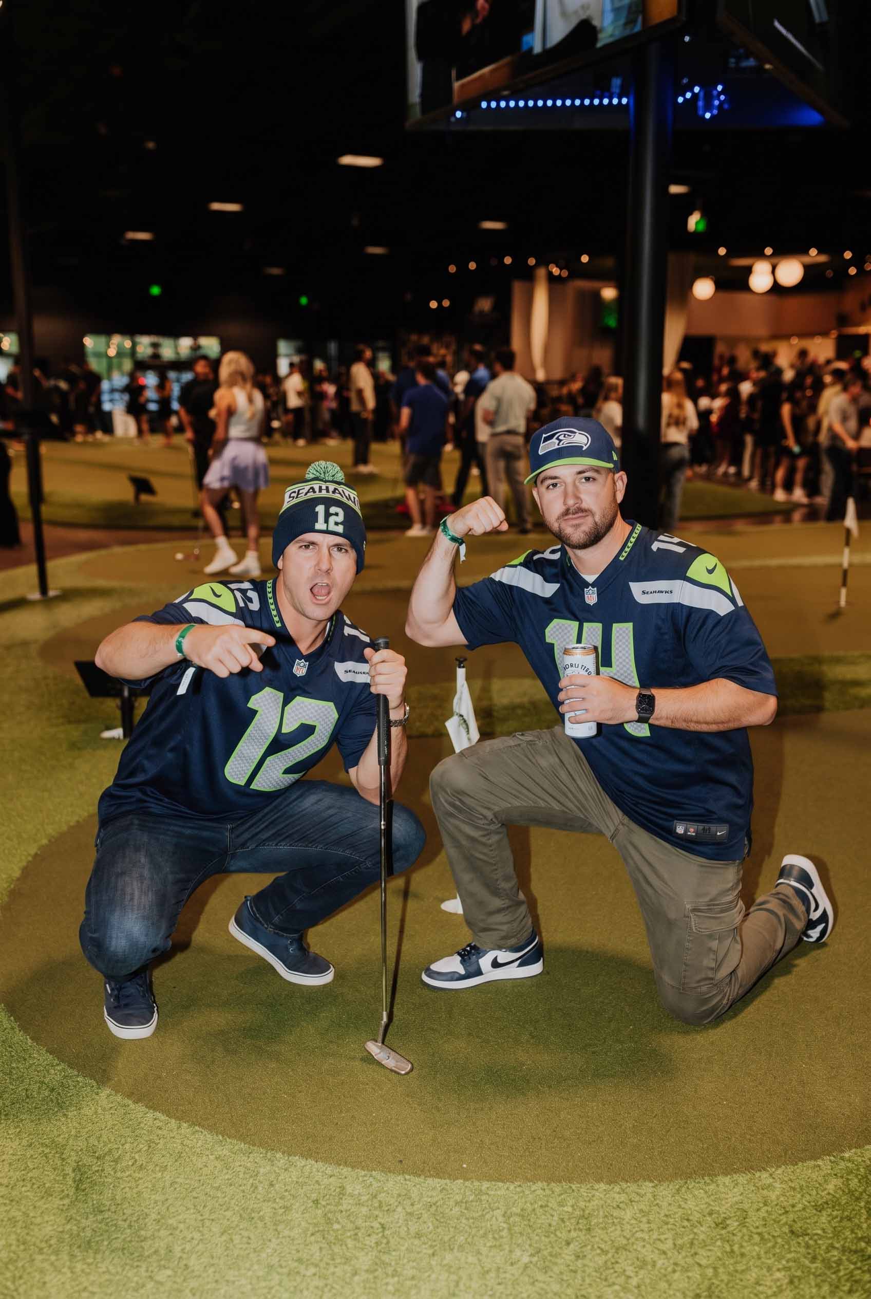 Two Seattle Seahawks fans kneeling with a putter on an indoor putting green at Putting World in Scottsdale