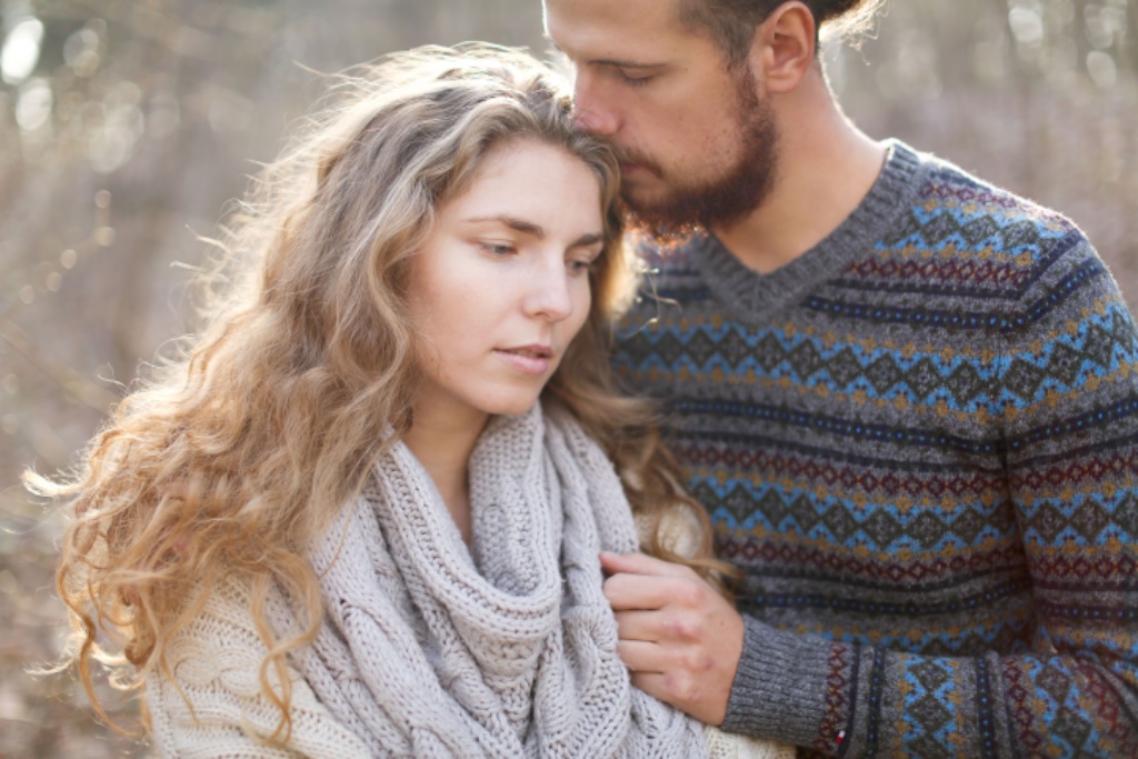 Couple embracing warmly outdoors in soft natural light — vulnerability and connection