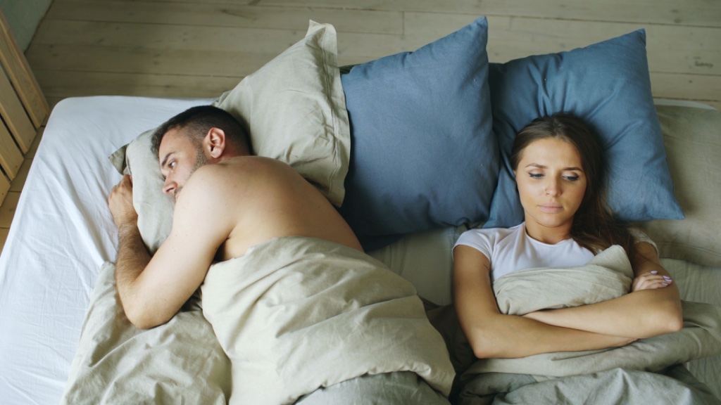 Couple lying apart in bed — emotional distance and insecure attachment