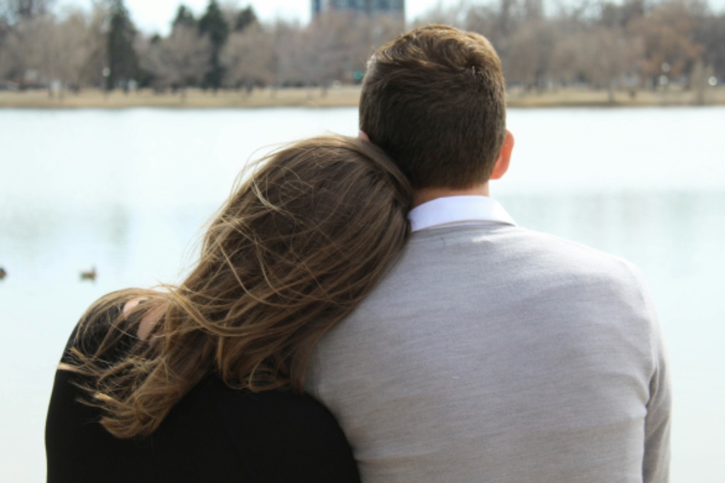 Couple sitting close together by the water — beginning to reconnect and rebuild trust