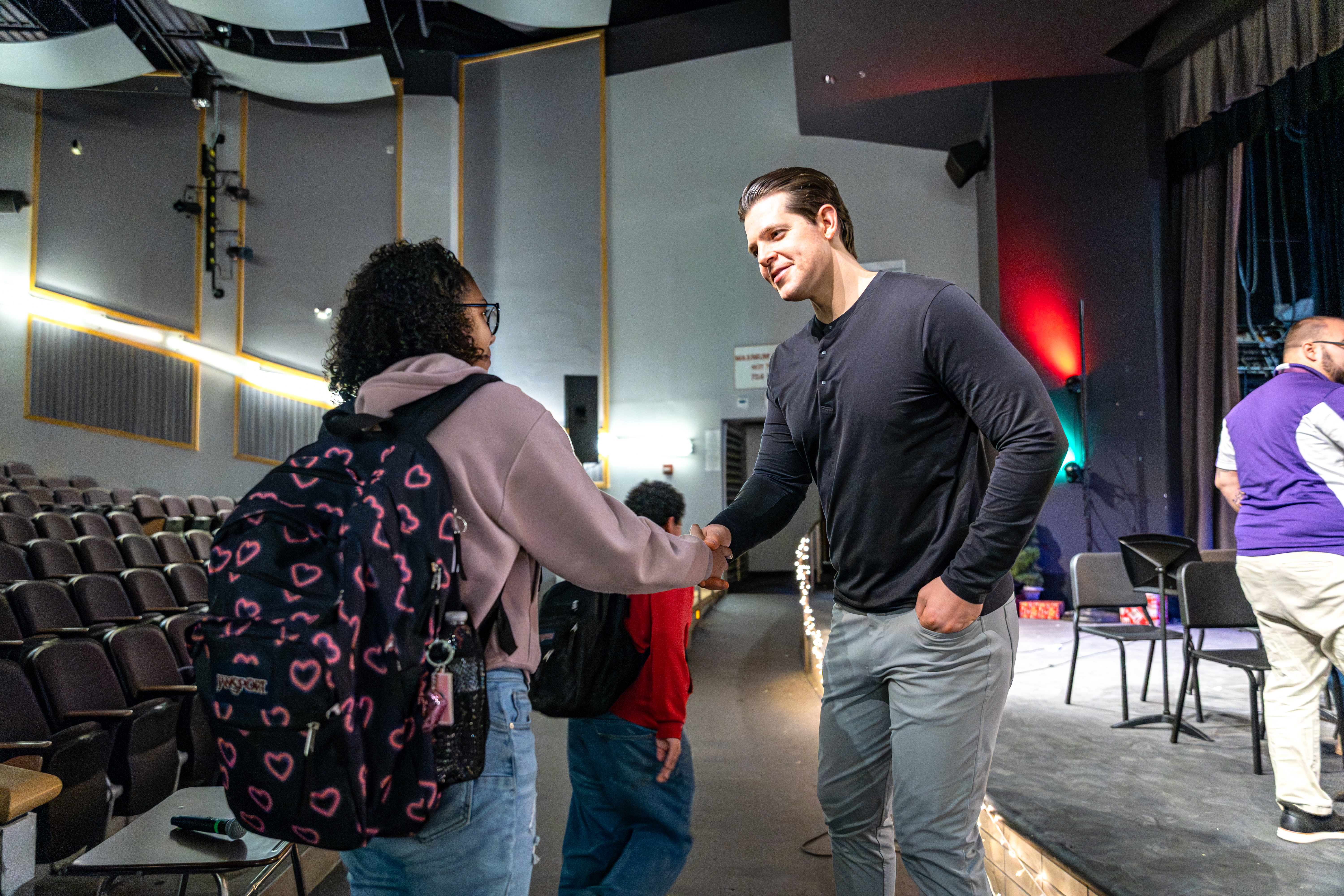 Stephen Hill shaking hands with a student in an auditorium