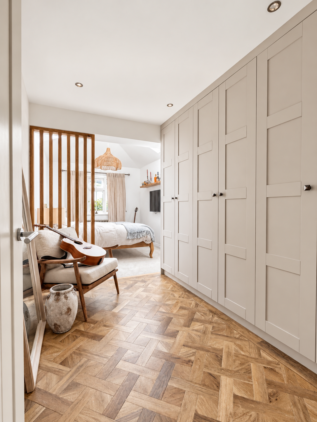 Bespoke fitted wardrobe with Shaker-style doors and herringbone parquet flooring